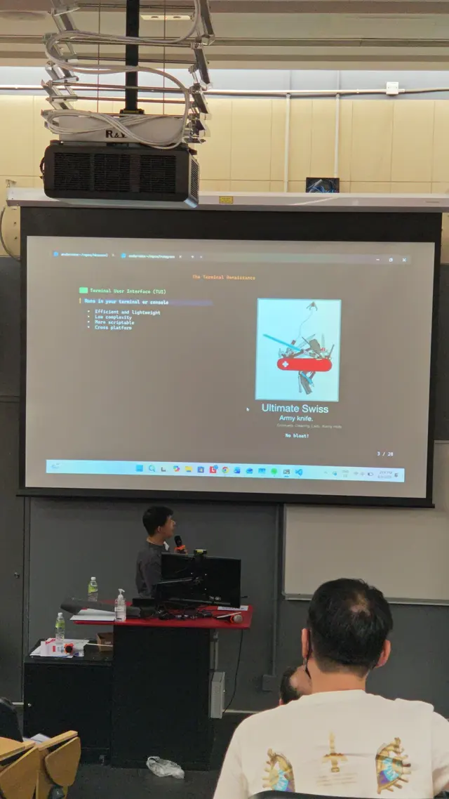 James presenting a slide about terminal user interfaces to an audience at a conference.