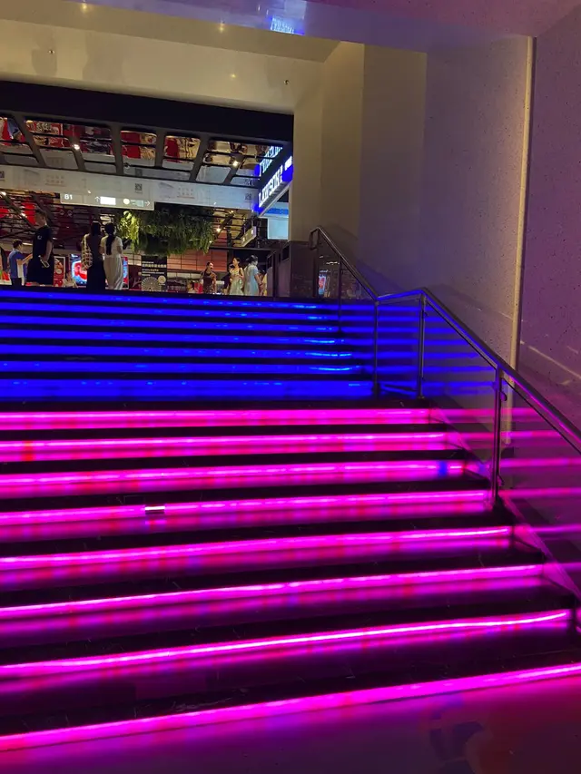 A staircase lit in blue and pink in a metro station