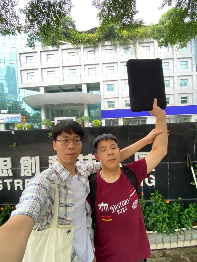 Two friends posing next to a Strength Building sign, creating a modern counterfeit of a heroic Soviet propaganda poster.
